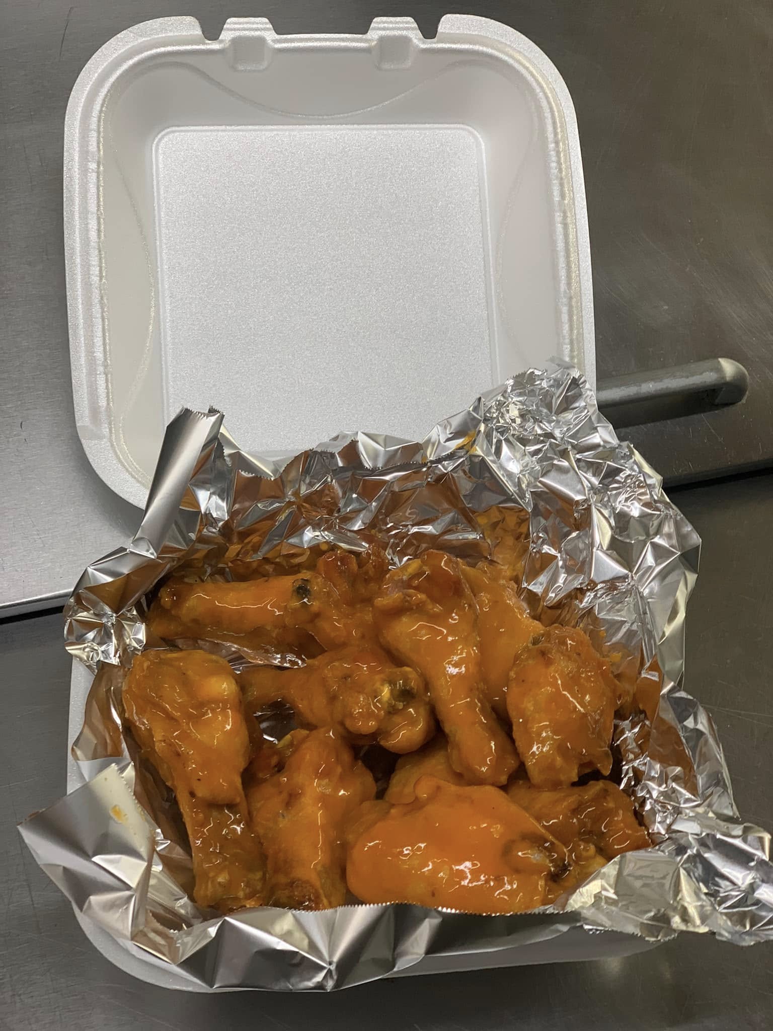 Buffalo wings with spicy sauce in takeout box